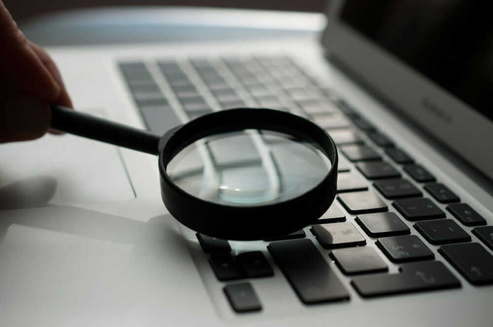 a magnifying glass searching for something on the laptop keyboard